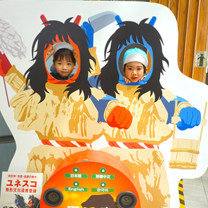 日本の伝統的な「なまはげ」の顔出しパネルから顔を出して楽しそうにしている2人の子ども