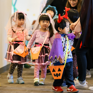 ハロウィンの仮装をした子供たち。一人は悪魔の角と紫色のマントを、他の二人はベールとドレスを着用している
