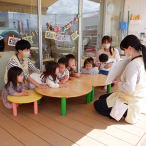 複数の子供と大人がテーブルを囲んでいる様子。部屋には鯉のぼりの飾りが吊るされている