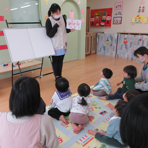 室内で先生の話を聞いている複数の子供たち