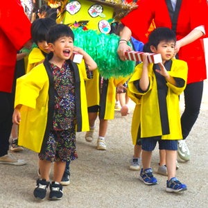 黄色い法被を着て、「わっしょい」と元気な声を出しながら手作りのお神輿を担いで歩く子どもたちの勇ましい姿。