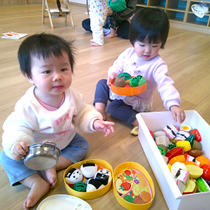 おにぎりやおかずのおもちゃを丁寧にお弁当箱に詰めて、おままごとを楽しんでいる二人の子ども。