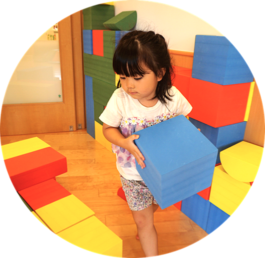 青い大きなソフトブロックを抱えて運ぶ女の子。