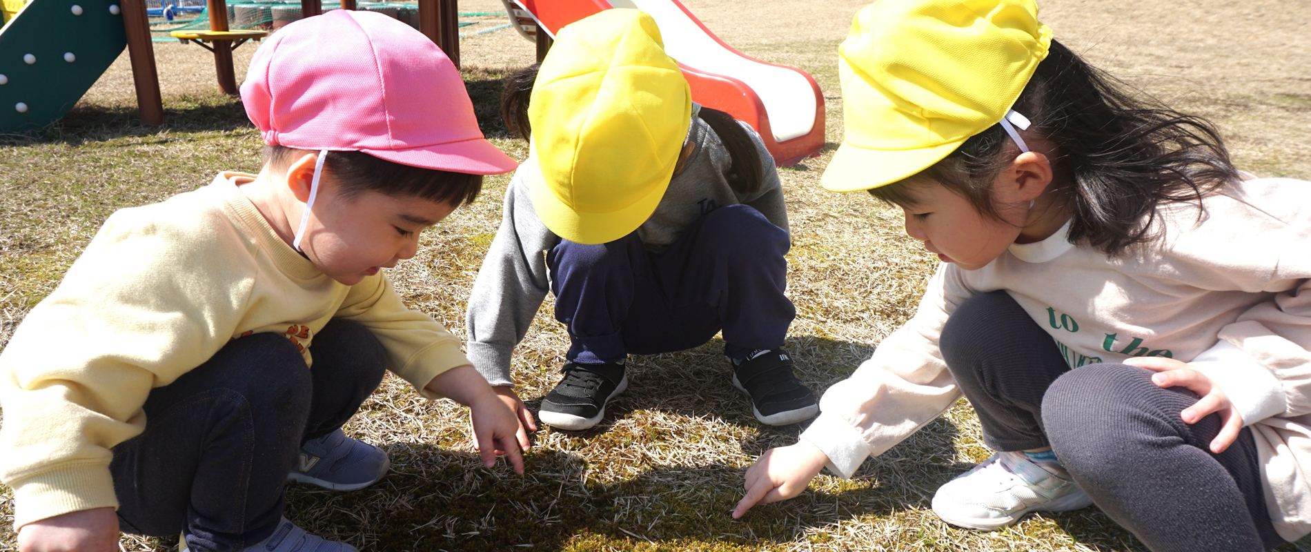 笑顔の2人の少女が新聞紙を広げた低い木製のテーブルでオレンジと青のおもちゃで遊んでいる。